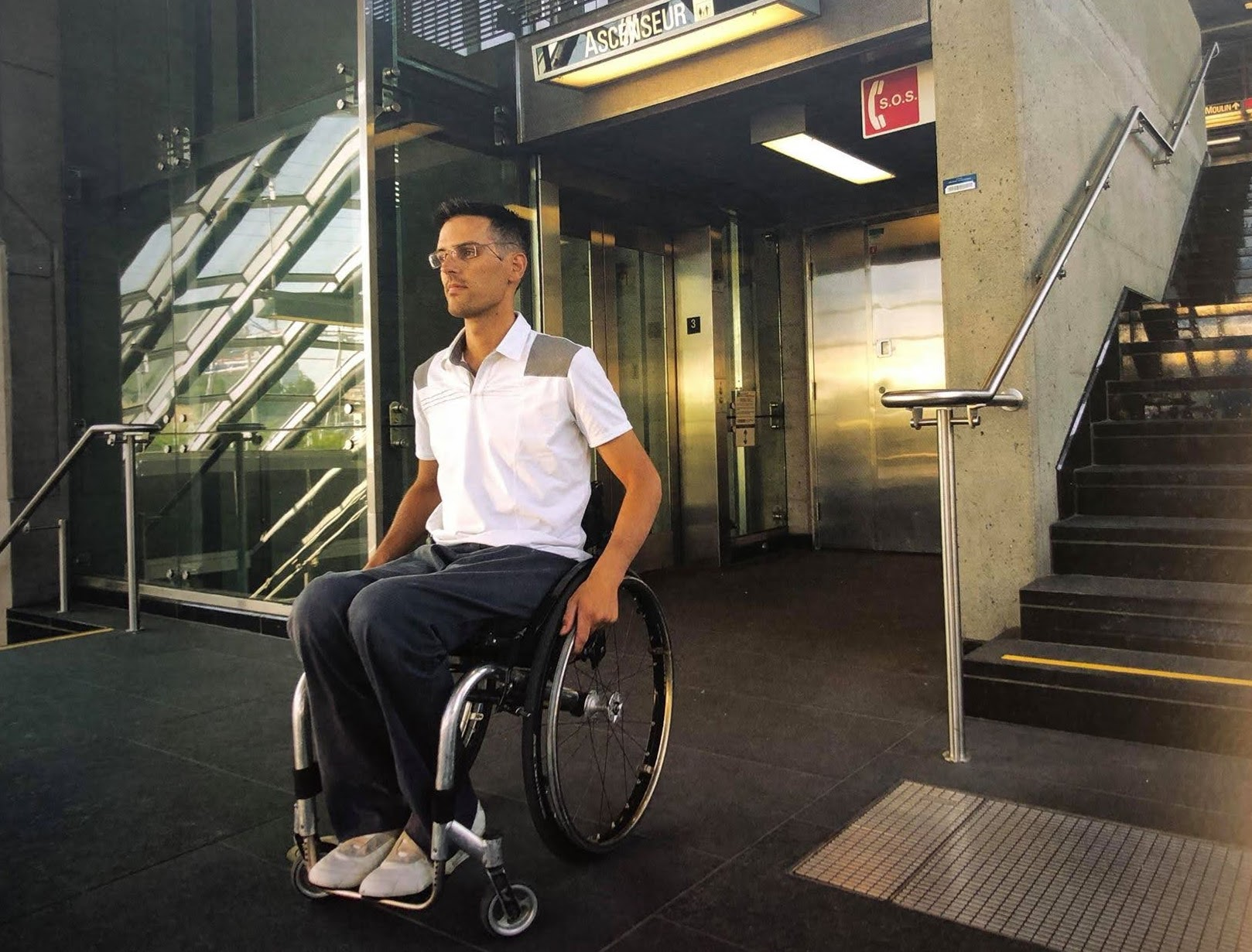 Maxime Jacottin sur son fauteuil roulant sortant d'un ascenseur dans une station de métro.